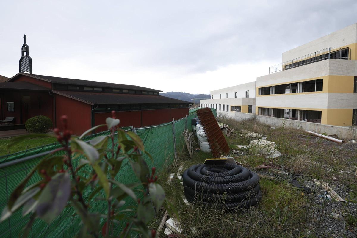 A la derecha, la residencia cuyas obras llevan paralizadas más de medio  año, con material apilado junto a la iglesia de Montecerrao.