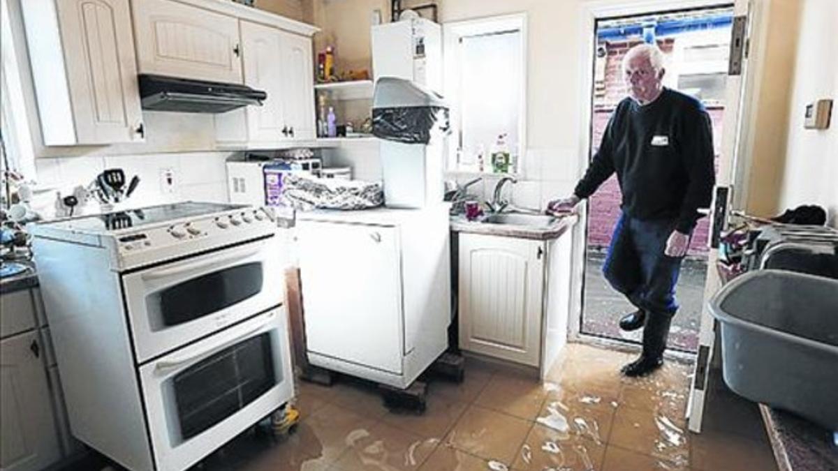 Michael Simmonds, de Eghan, camina por la cocina de su casa inundada.