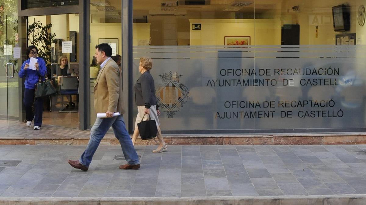 Dos ciudadanos pasan frente a la ofucina de recaudación del Ayuntamiento de Castellón situada en la calle Gobernador.