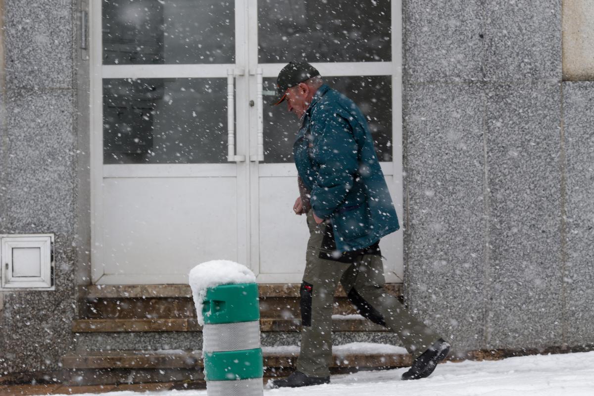 Un hombre camina por una calle cubierta de nieve,