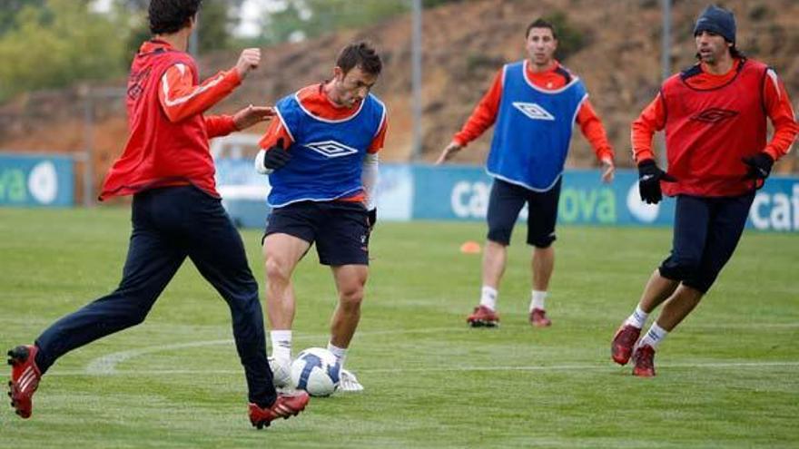 George Lucas conduce el balón ante la oposición de Noguerol, de espaldas, y Jordi y en presencia de Roberto Lago durante el entrenamiento de ayer en A Madroa.