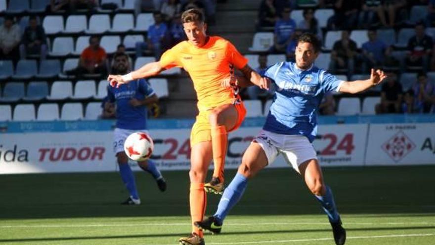 El migcentre canari del Llagostera Leo Ramírez lluita per una pilota amb un futbolista del Lleida Esportiu.