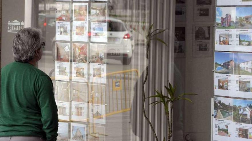 Un hombre mira los anuncios de pisos en venta y en alquiler en una inmobiliaria de A Coruña.