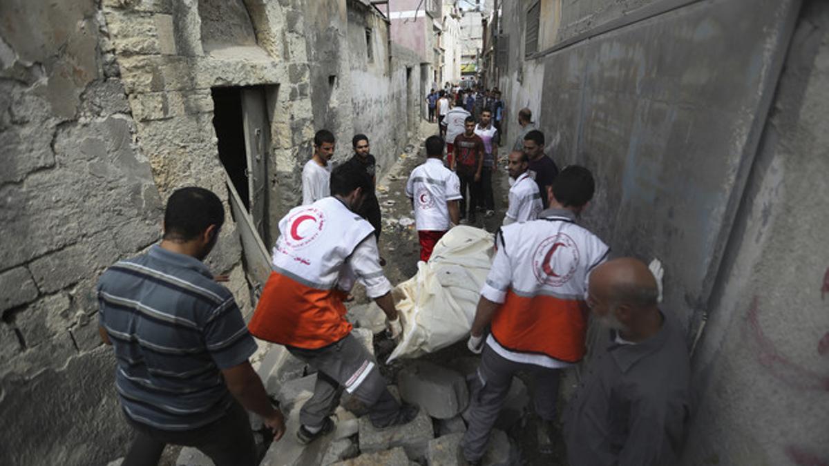 Médicos palestinos evacuan un cadáver en el barrio de Shayahía, este domingo.