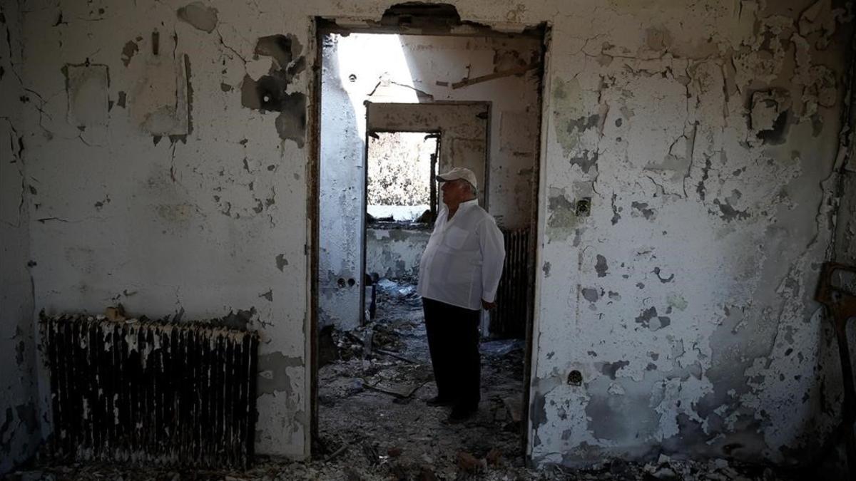 Un hombre en su casa quemada de Mati.