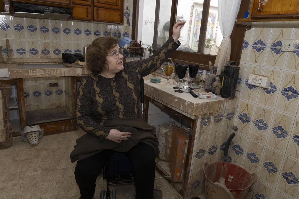 Mª Ángeles marca con la mano el nivel que alcanzó el agua junto al banco de la cocina en el que se llegó a refugiar.