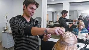 Un trabajador autónomo atiende a una clienta en su peluquería de Barcelona.