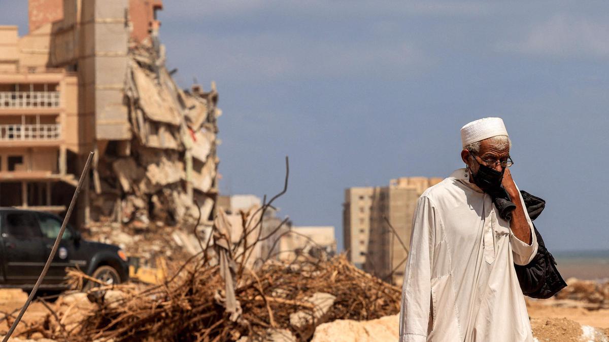 Un hombre con mascarilla pasa frente a un edificio en ruinas en la ciudad libia de Derna, este lunes.