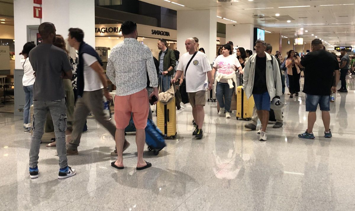 Tres taxistas pirata, de espaldas, ofreciendo sus servicios en la terminal de llegadas del aeropuerto de Ibiza.