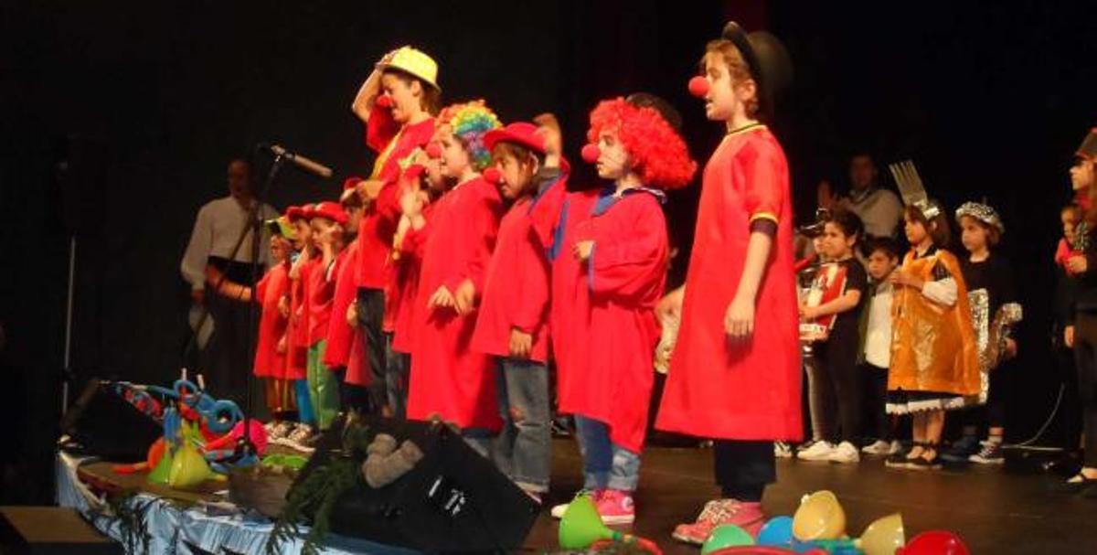 Los alumnos disfrazados de payasos, cantando. A la derecha, los niños bailan la danza prima.