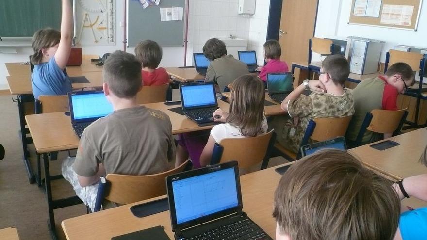 Niños y niñas en clase con los ordenadores.