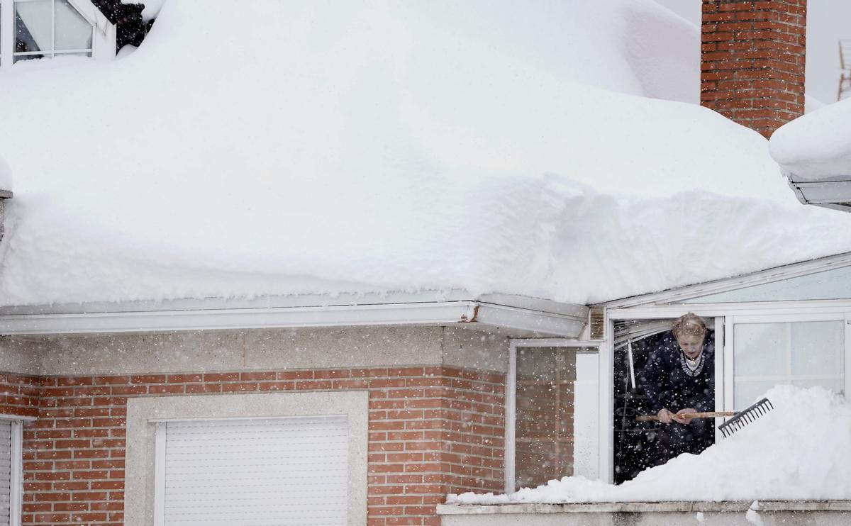 Una mujer quita nieve del tejado de su casa durante el temporal de nieve en Madrid por la borrasca Filomena.