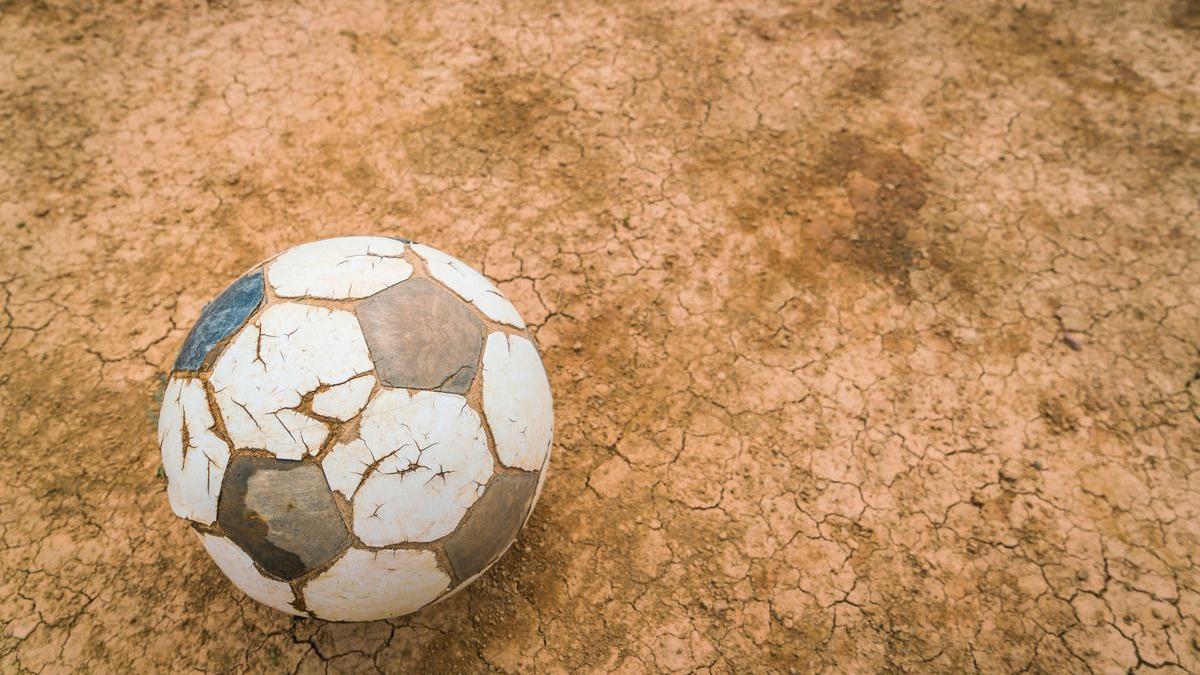 Un viejo balón de cuero sobre un campo de tierra, iconos del romanticismo de un fútbol que ya no volverá