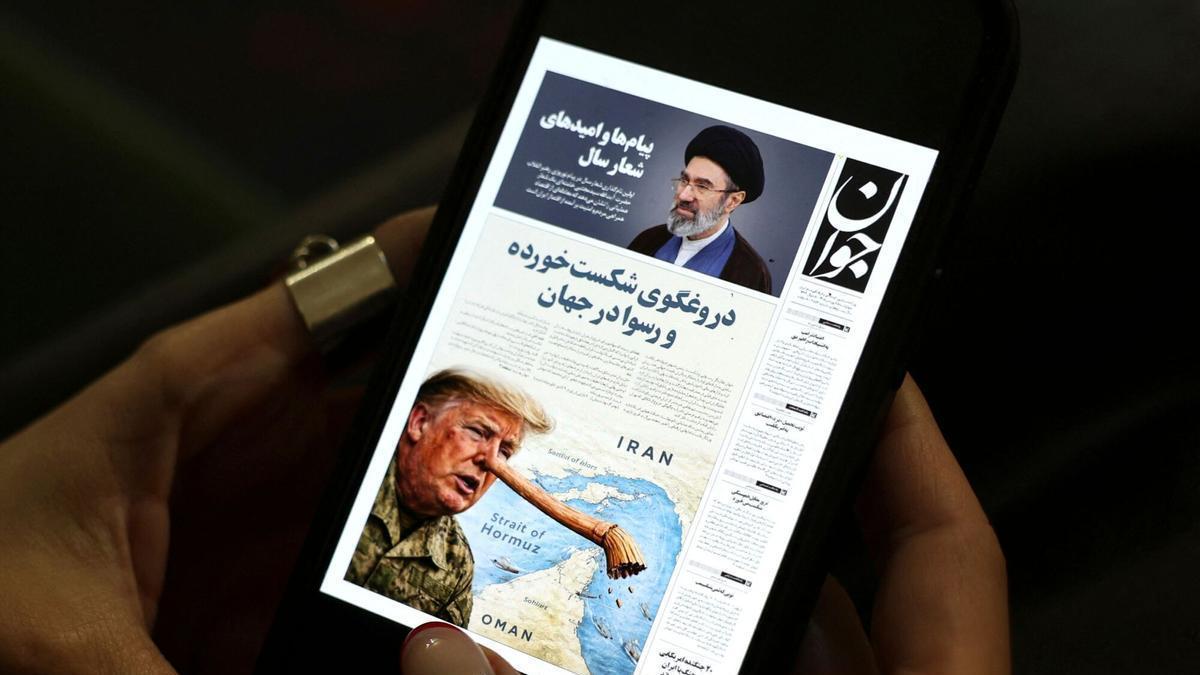 Una iraní lee el diario Javan en su móvil, este miércoles en Teherán, donde se ridiculiza a Trump por asegurar que está en conversaciones con el régimen.