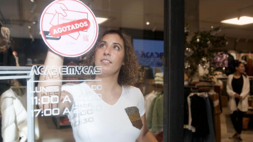 Sara G. Balbuena, ayer por la mañana, colocando el cartel de «agotados» del plan de bonos en su tienda de ropa de la calle Domínguez Gil. | Marcos León