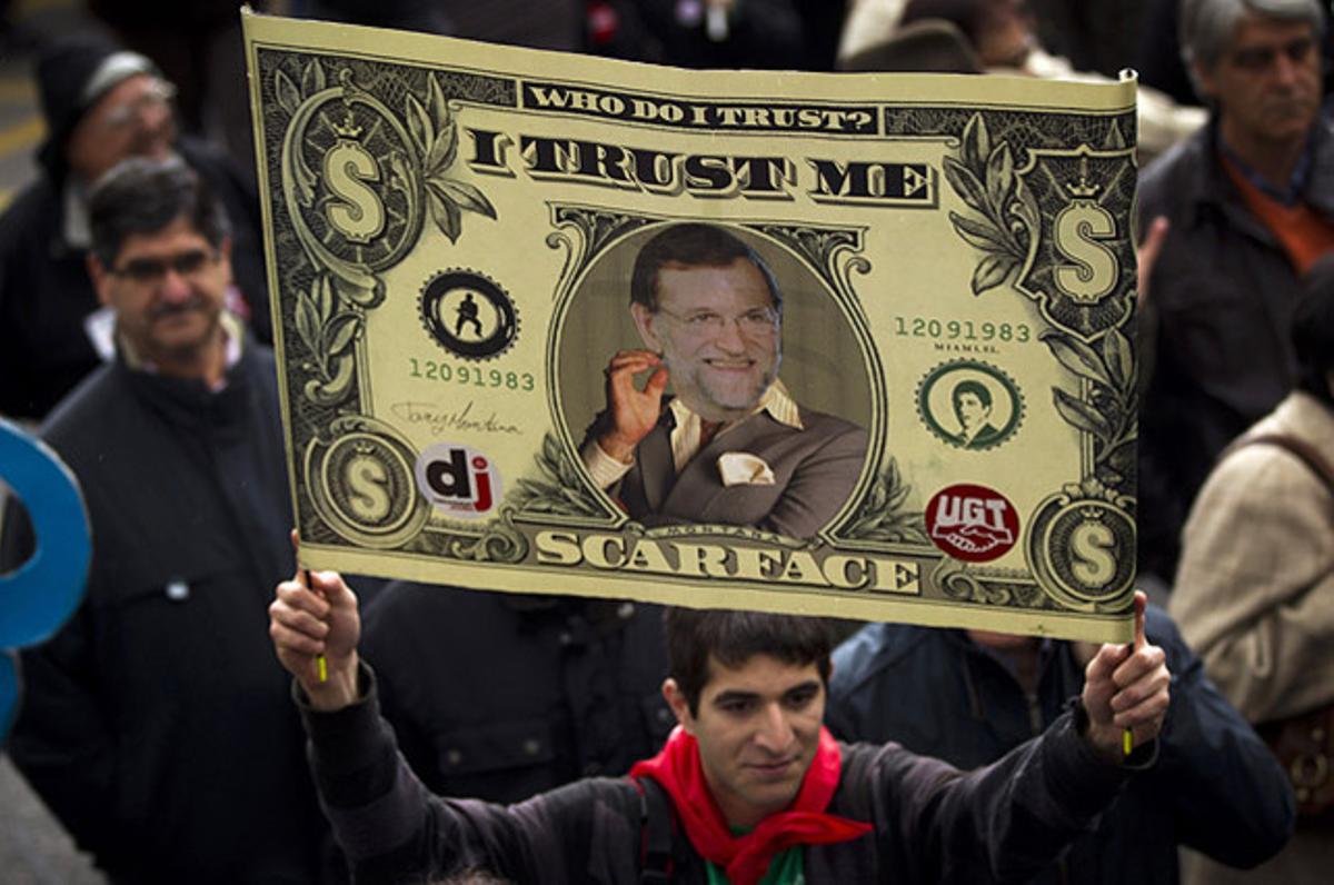 Un manifestant el Dia Internacional dels Treballadors a Madrid mostra una pancarta contra la política d’austeritat del Govern de Mariano Rajoy.