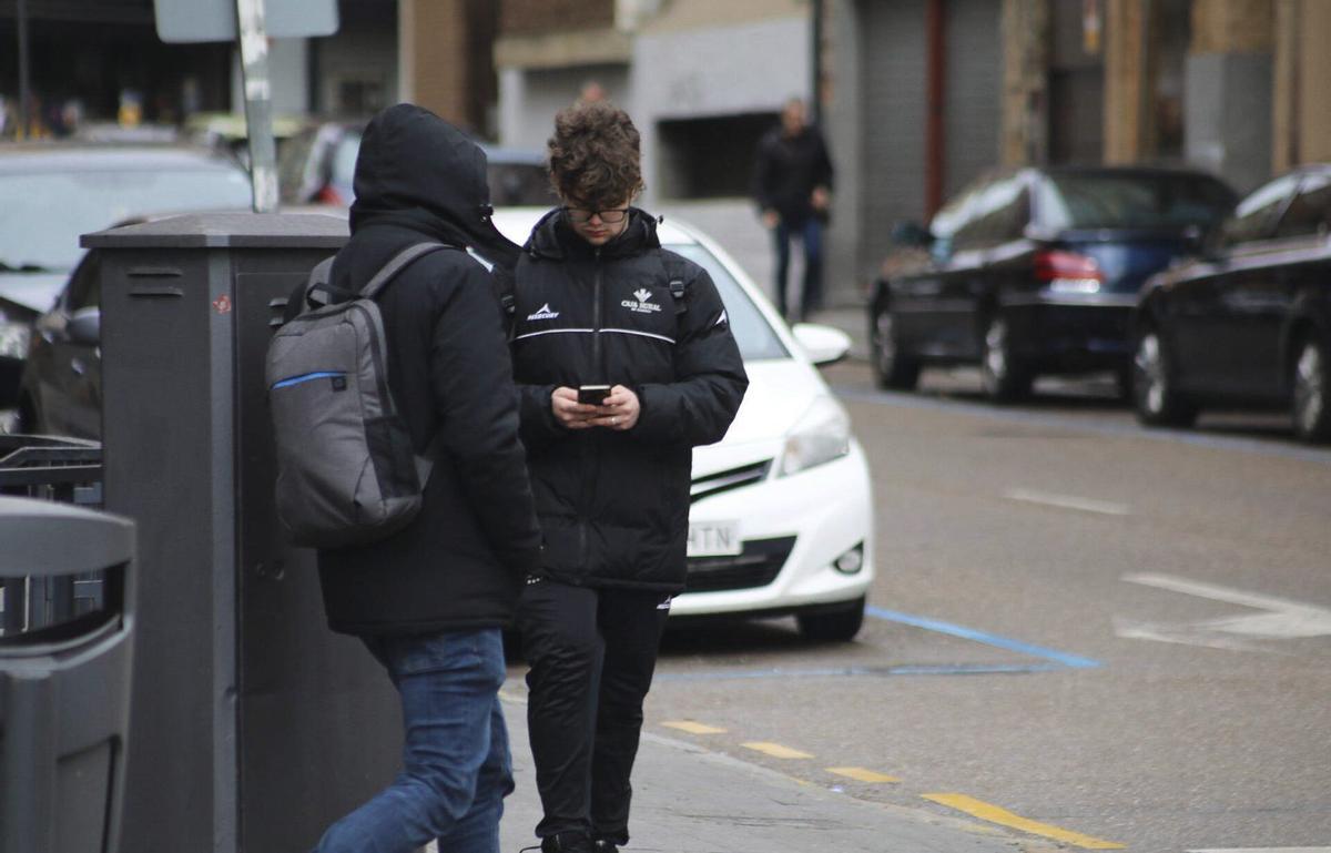 Un menor utiliza su móvil mientras su amigo le mira. | ALBA PRIETO