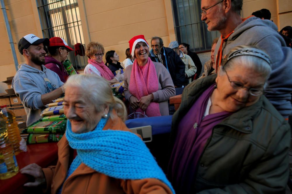 People wait to receive food during a daily food ...