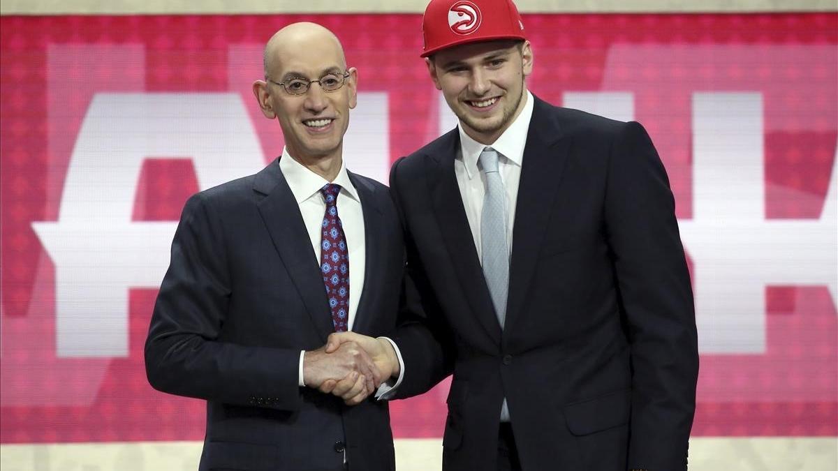 Luka Doncic saluda en el estrado a Adam Silver, comisionado de la NBA, tras su elección