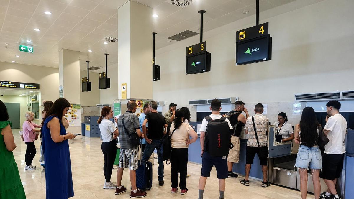 Pasajeros ante el mostrador de Talavera la Real tras conocer que su vuelo a Barcelona había sido cancelado sin alternativas, este domingo.