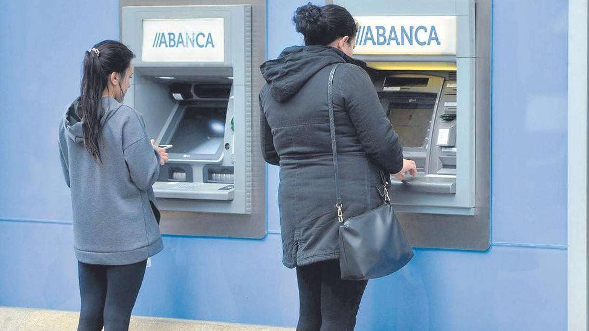 Imatge d’arxiu de dues dones operant en caixers automàtics. | G.SANTOS