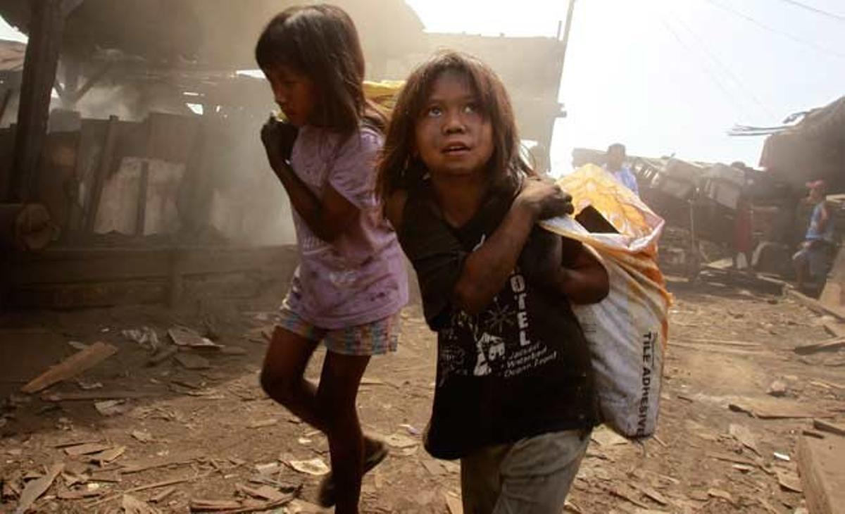 Dues nenes carreguen sacs de carbó vegetal en una fàbrica d’un suburbi de Manila (Filipines).
