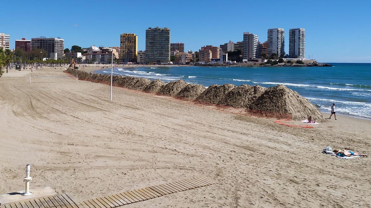 Una persona tomando el sol junto a los acopios de arena.