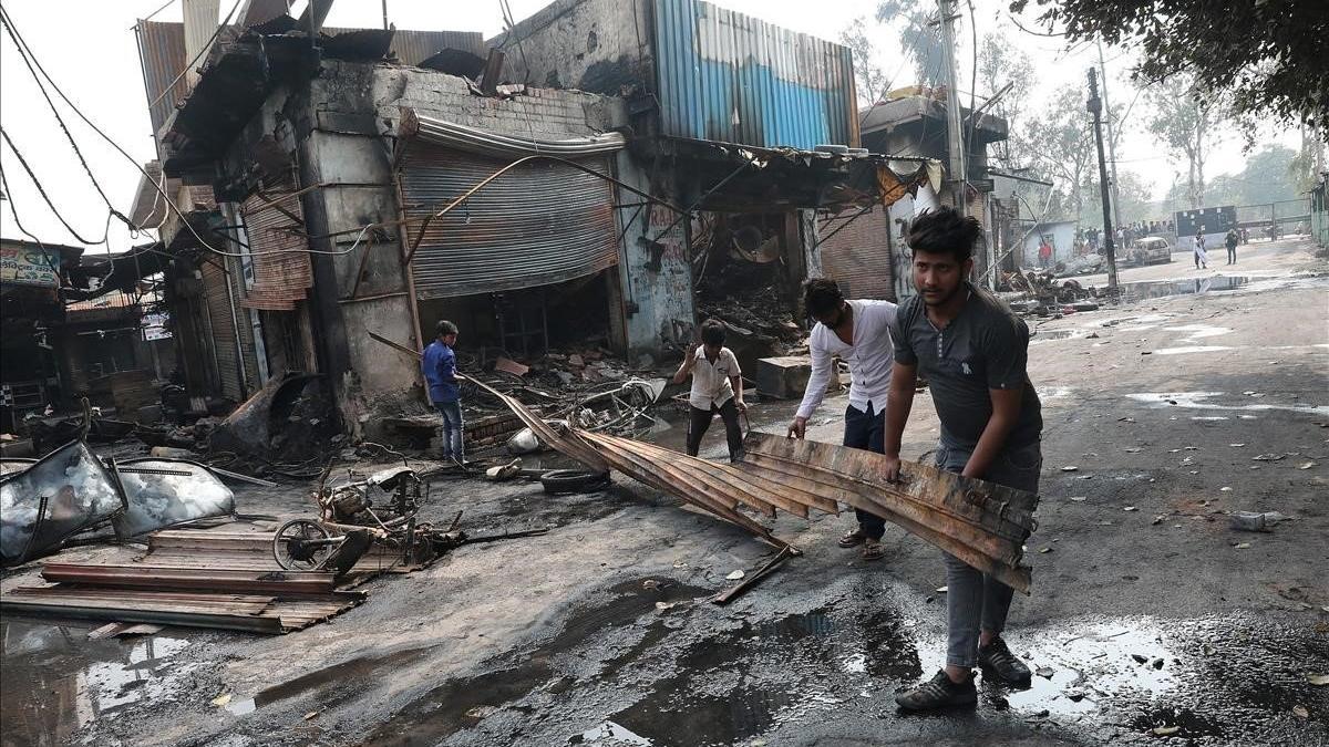 Varios hombres sacan material quemado de un edificio afectado por las protestas entre hindús y musulmanes en Nueva Deli, este miércoles.