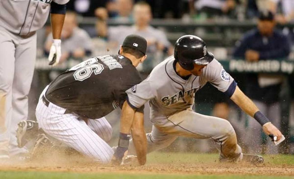 El jugador dels Seattle Mariners Dustin Ackley anota mentre el pitcher dels Florida Marlins Steve Cishek intenta evitar-ho en la desena entrada d’un partit de beisbol a Seattle, diumenge.