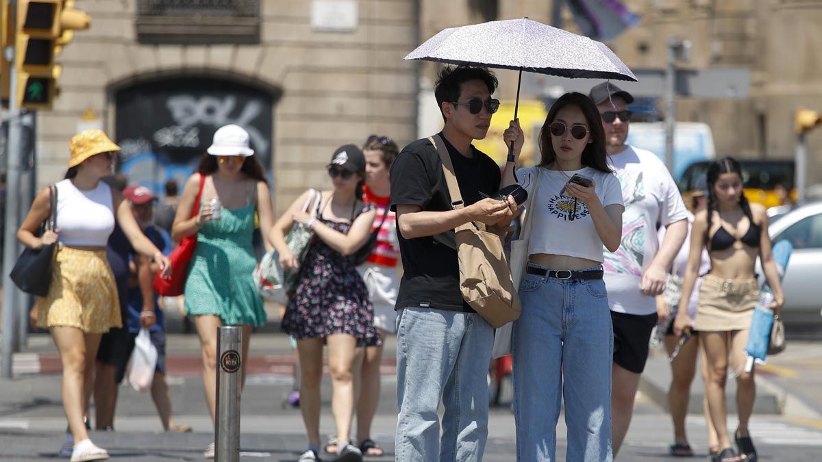 Unos turistas pasean por el centro de Barcelona, todas las comarcas de Cataluña entran en el máximo nivel de alerta por la ola de calor, que alcanza su pico con temperaturas que superarán los 41 °C en la 'plana' de Lleida.