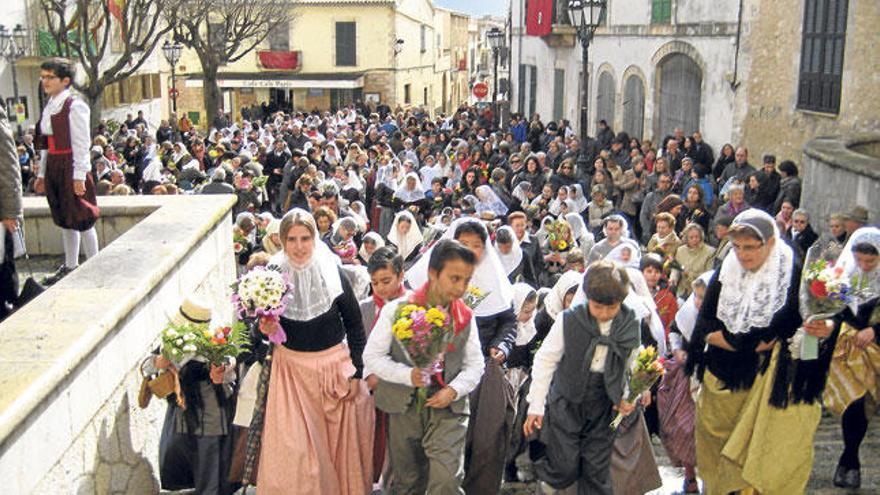 Payeses y payesas efectúan la ofrenda floral a la Beata al pie de la escalinata de la iglesia.