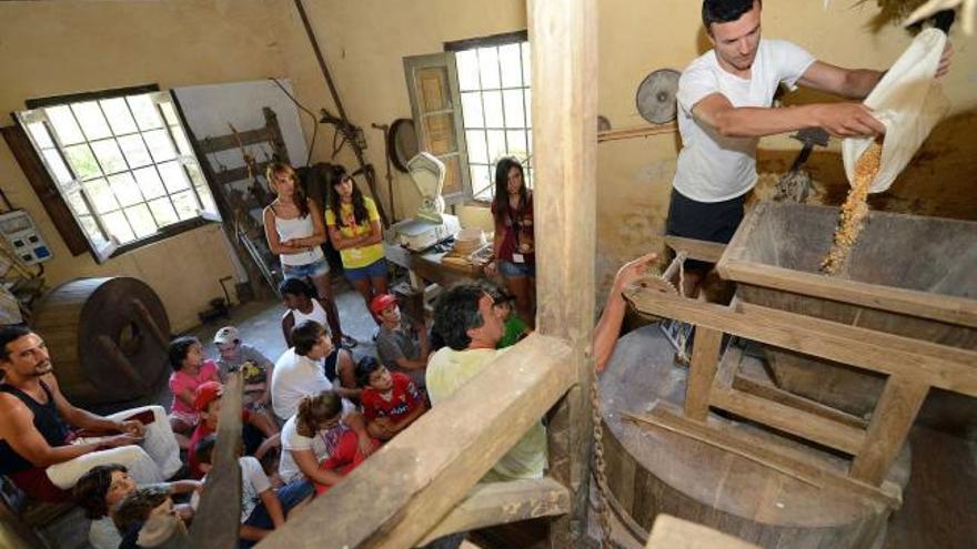 Ricardo Cordero explica a los niños el funcionamiento del molino de Agüeria, en Aller.