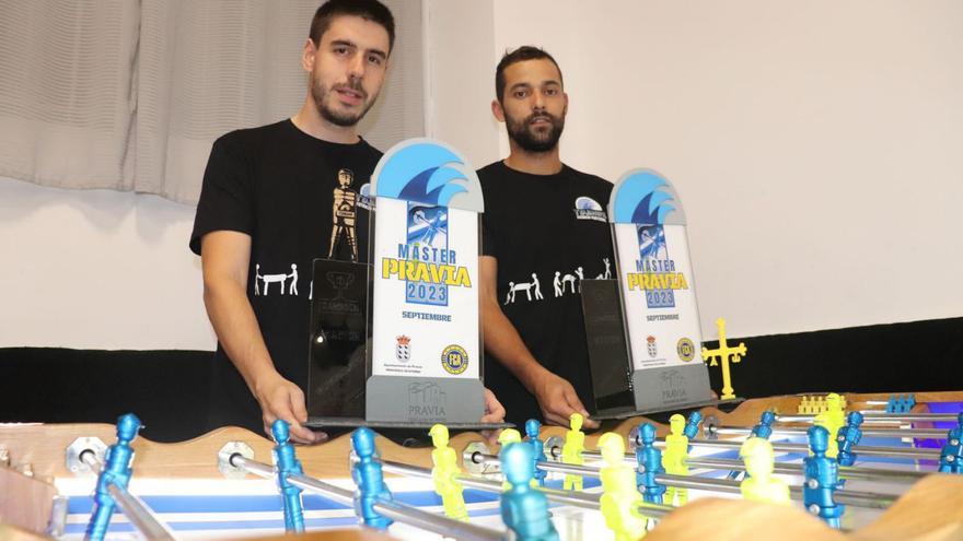 Marco Foxo y Yago Vilas, con sus trofeos de campeones, junto al futbolín en el que entrenan.