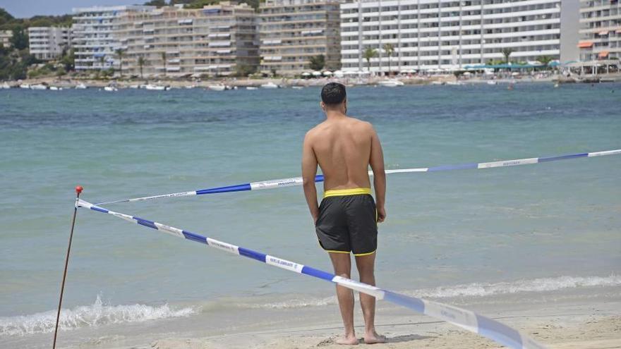 Un bañista observa el mar junto a las cintas de precinto que impiden el acceso al agua.