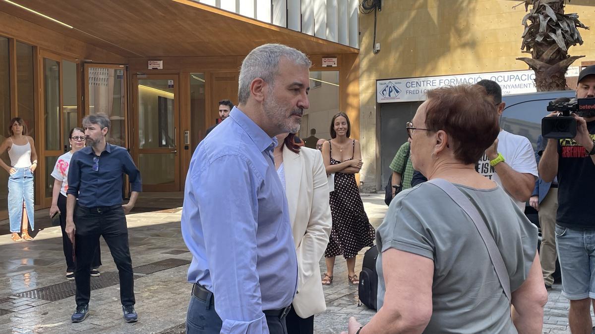 Jaume Collboni conversa con una vecina de Ciutat Vella (Barcelona) delante del edificio del nuevo centro de alojamientos temporales, este martes.