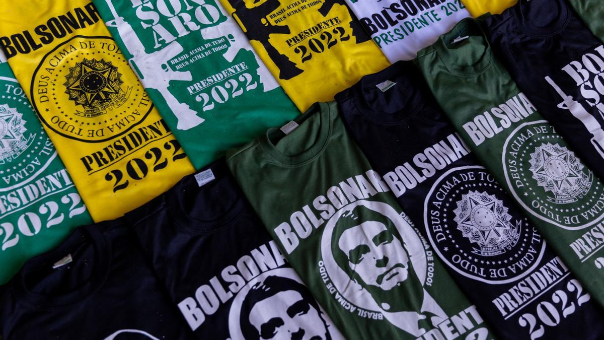 Camisetas con el rostro y el nombre de Bolsonaro entre fusiles de asalto en una calle de Brasilia, este lunes.