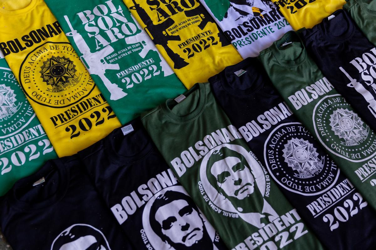 Camisetas con el rostro y el nombre de Bolsonaro entre fusiles de asalto en una calle de Brasilia, este lunes.