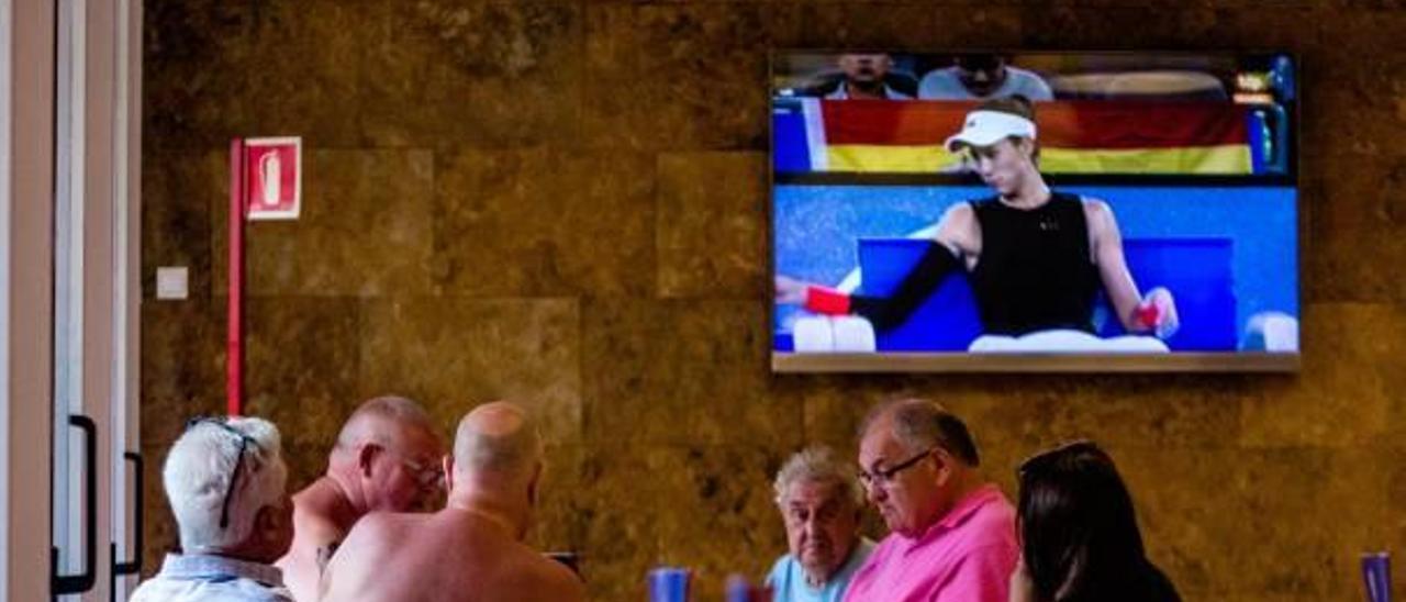 Turistas en la cafetería de un hotel de Benidorm, con la televisión puesta de fondo.