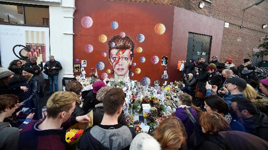 Seguidores y admiradores de David Bowie, ayer ante el mural en una calle del barrio londinense de Brixton, donde nació el cantante en 1947.