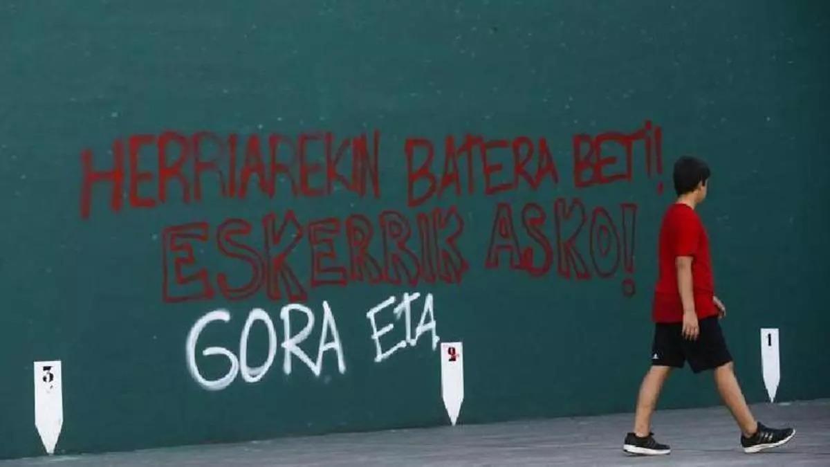 Un menor passa davant una pintada realitzada a favor d'ETA en un frontó d'Hernani (Guipúscoa)