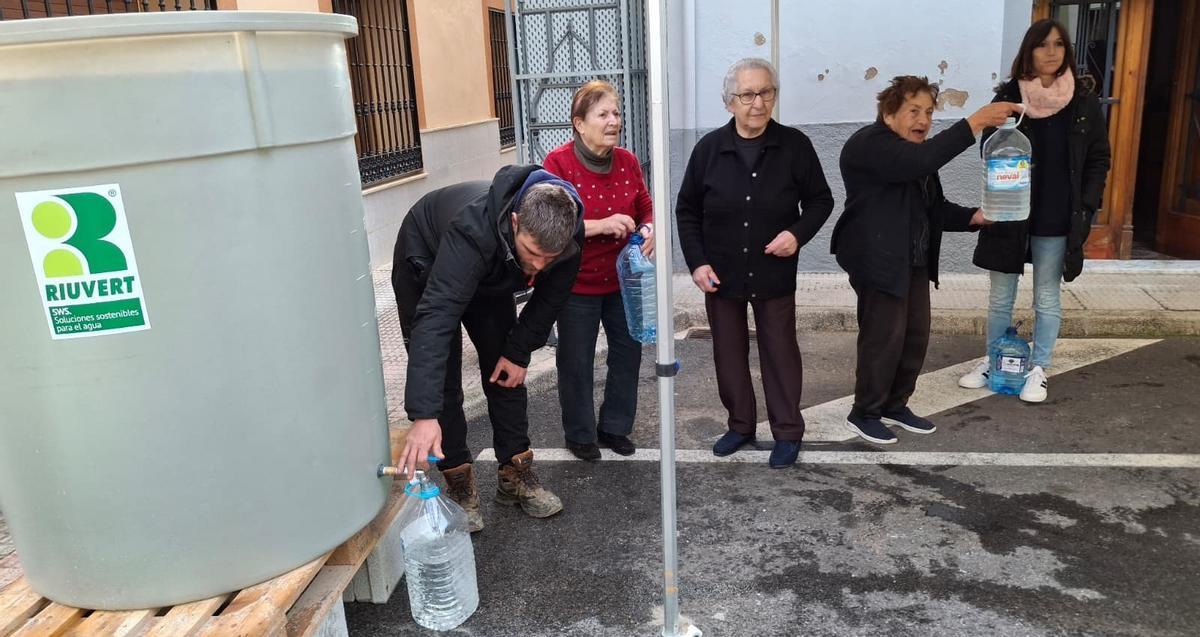 Los vecinos llenan garrafas en un depósito instalado en la calle