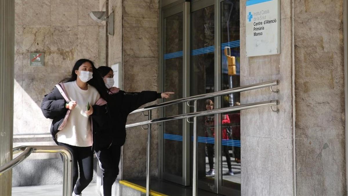 Dos chicas con mascarilla, por el riesgo de coronavirus, frente al CAP Manso, en Barcelona