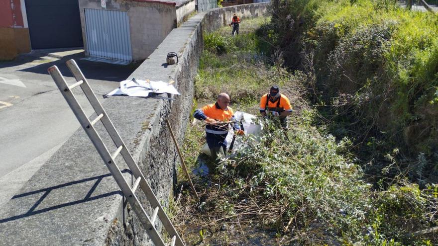 Operarios trabajan en la limpieza del río Triana, ayer, a la altura de Sama. | M. Á. G.