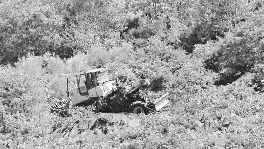 Un bulldozer (izq.) trata de levantar los restos del tractor, ayer. // J. Regal