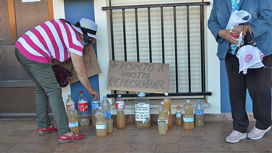 Dos vecinas de Bercianos dejando la muestra del agua supuestamente potable que sale del grifo de sus casas.. | E. P.