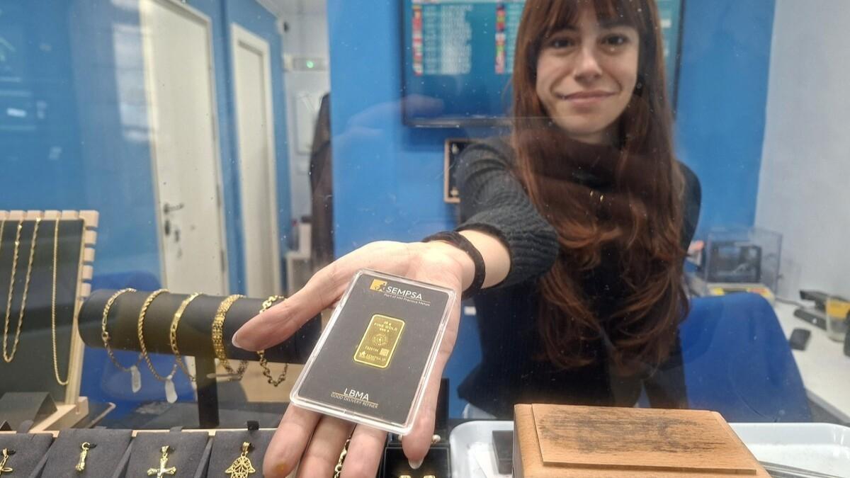 Una empleada de la tienda Quickgold de Santiago con un lingote de 20 gramos de oro
