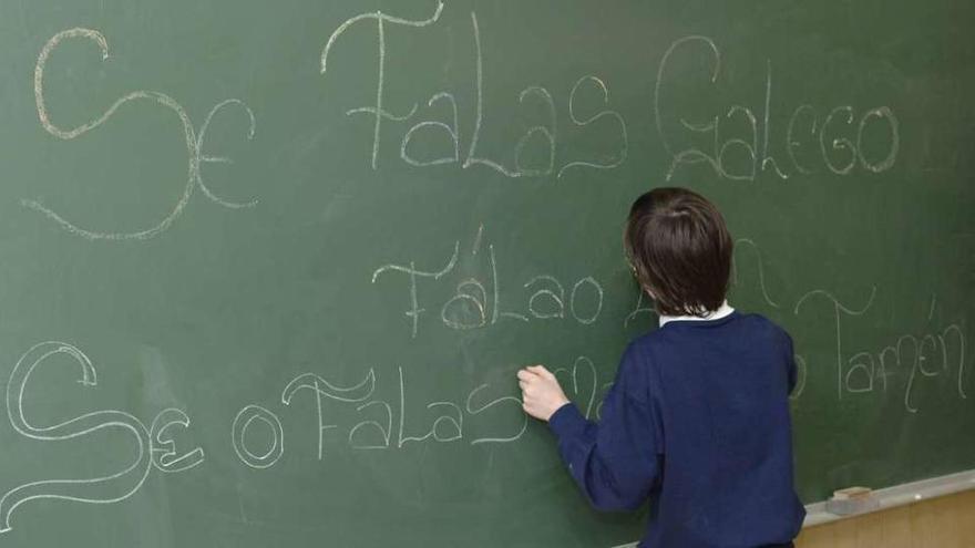 Un niño escribe en gallego en la pizarra de su clase.