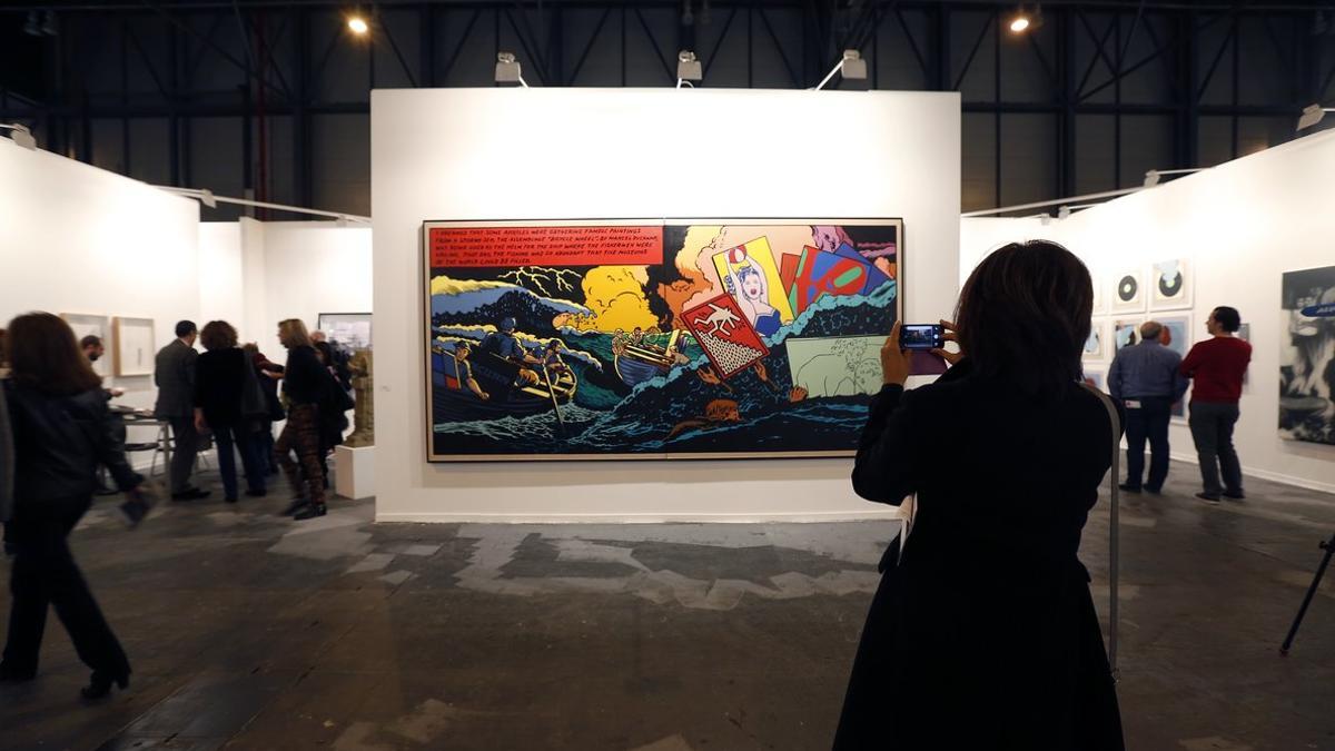 Una mujer fotografiando un cuadro expuesto en la feria ARCO Madrid