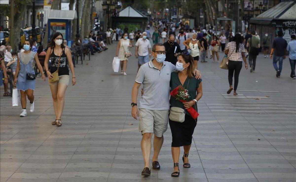 Gente con mascarilla pasea por la Rambla de Barcelona.