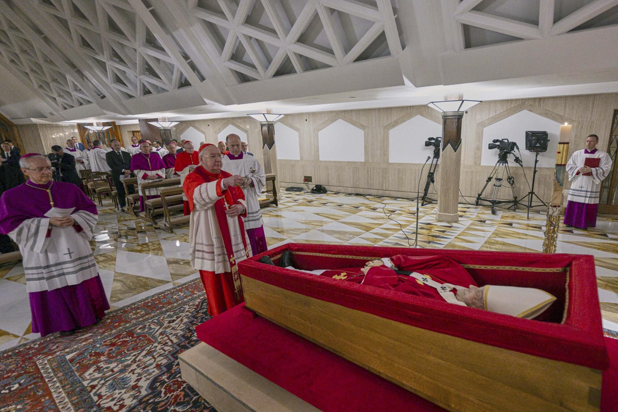 Cardinal Camerlengo Kevin Joseph Farrell, center, flanked by Master of Ceremonies Archbishop Diego Giovanni Ravelli, left, and Master of Ceremonies Lubomir Welnitz, right, performes the ceremonial aspersion of the body of Pope Francis with holy water as part of the final rites inside his private chapel at the Vatican, Monday, April 21, 2025. (Vatican Media via AP, HO) Associated Press/LaPresse. EDITORIAL USE ONLY/ONLY ITALY AND SPAIN